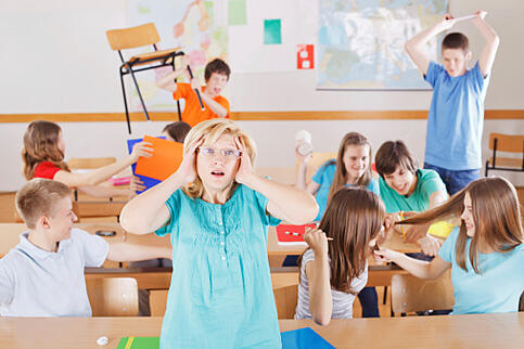 Image of a stressed teacher in a classroom with students